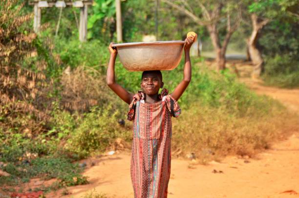 istock Girl Carrying Container On Head Against Trees 1156494472