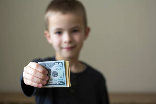 istock Cheerful blurred boy showing american dollars money. 1156494479