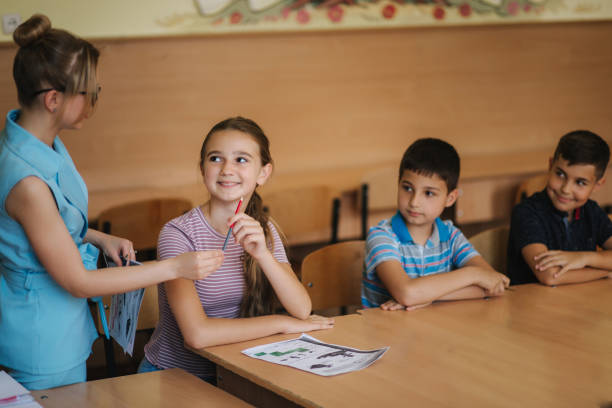 istock Teacher helping school kids writing test in classroom. education, elementary school, learning and people concept 1156495108