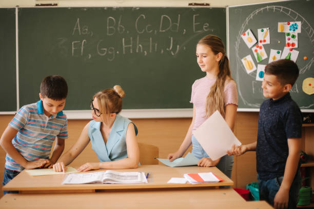 istock Young teacher check childrens work. Schoolboy and schoolgirl study 1156498988