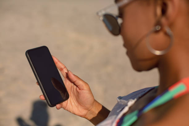 istock Woman using mobile phone at beach in the sunshine 1156503748