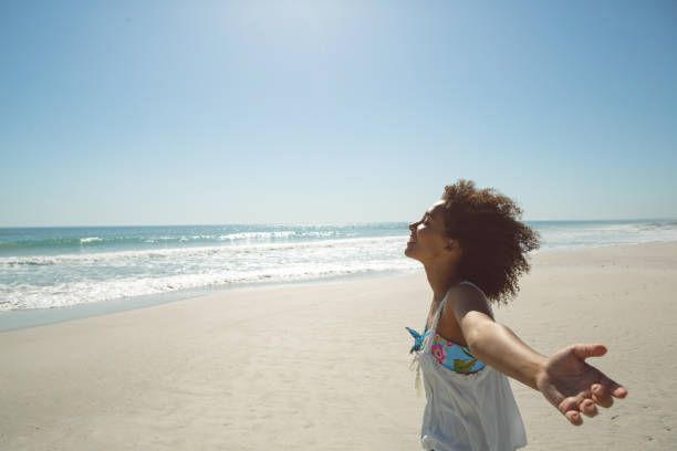 istock Woman standing with arms outstretched on the beach 1156506482
