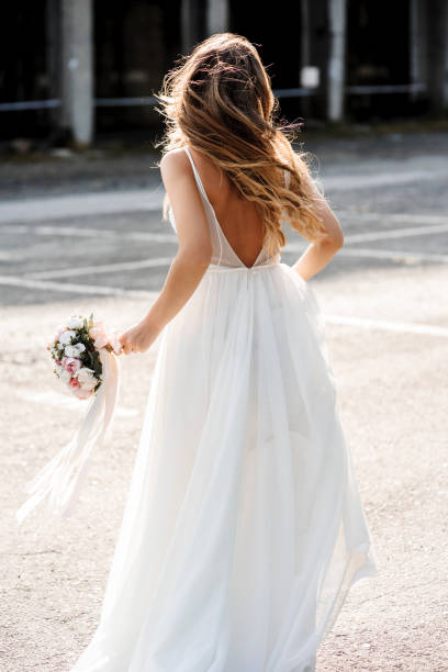 istock Back view unrecognizable bride running with a bucket in her hands on the street. 1156506856