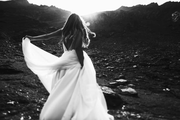 istock Back view of a unrecognizable bride dancing in the mountains against sunrise. 1156506885