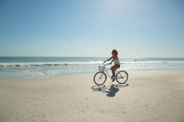 istock Woman riding a bicycle at beach on a sunny day 1156507255