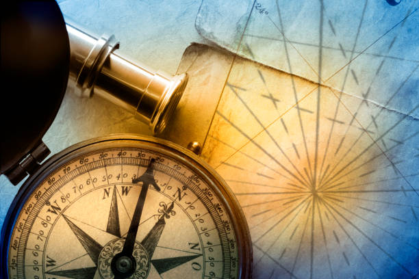A compass and a spyglass rest on the converging navigational lines of an old map.