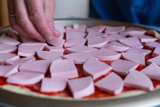pizza dough smeared with ketchup and with slices of sausage as background