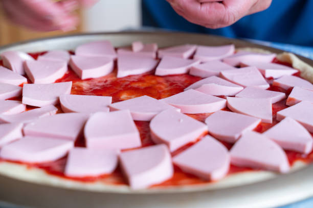 pizza dough smeared with ketchup and with slices of sausage as background