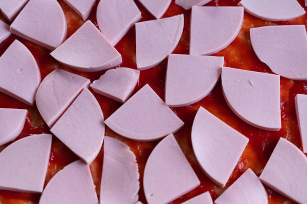 pizza dough smeared with ketchup and with slices of sausage as background