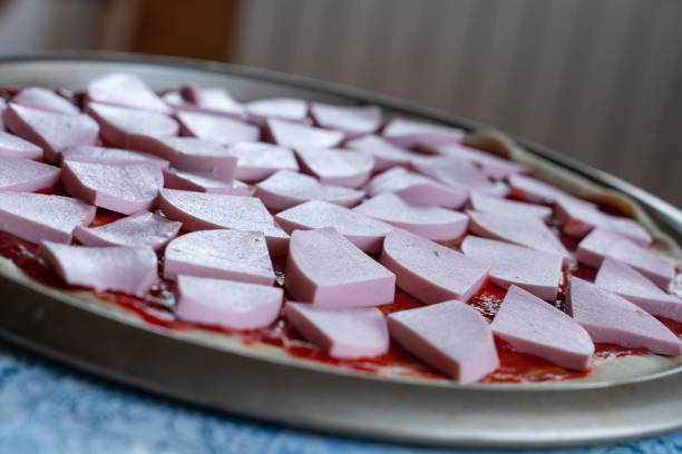 pizza dough smeared with ketchup and with slices of sausage as background