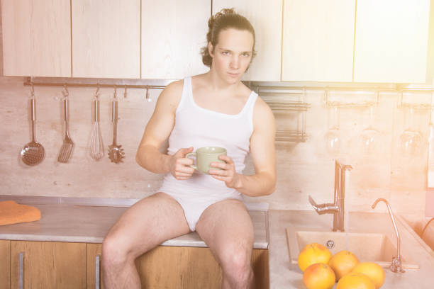 istock Young sexy guy in the kitchen is drinking coffee. 1156509925