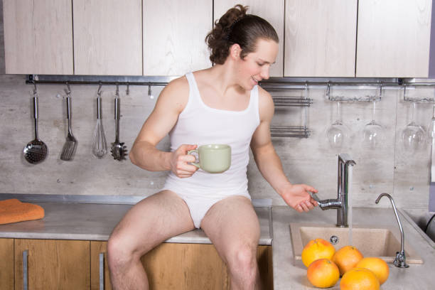 istock Young sexy guy in the kitchen is drinking coffee. 1156510086