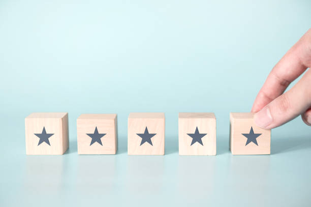 Woman Hand putting wooden five star shape on blue background.