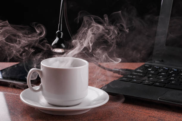 istock LED USB lamp connected to laptop and looking into coffee cup from which steam comes. Concept of alive usb-lamp. 1156512307