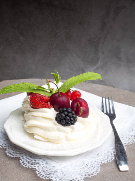 istock Rustic Pavlova cake with fresh strawberries, cherrys, blackberrys, mint and whipped cream over concrete background. 1156513604