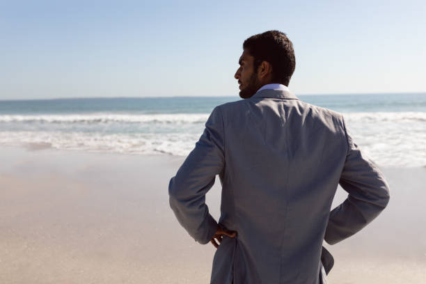 istock Young Businessman standing with hands on hips at beach 1156514366
