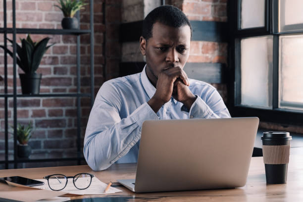 istock Serious african american business man working on project at modern loft office, thinking about financial troubles 1156514370
