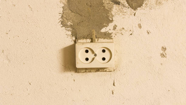 istock Electrical outlet on the old concrete wall. Isolated on light background. 1156515679