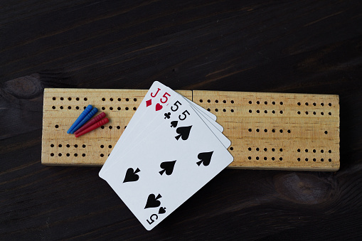 playing cards with cribbage board on black background