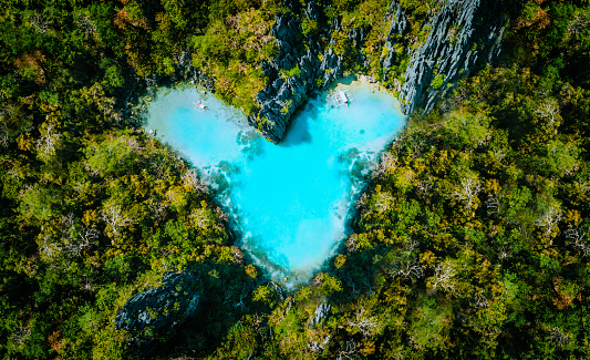 Aerial top view of turquoise lagoon shaped heart inside of tropical island. Love travel summer vacation concept.