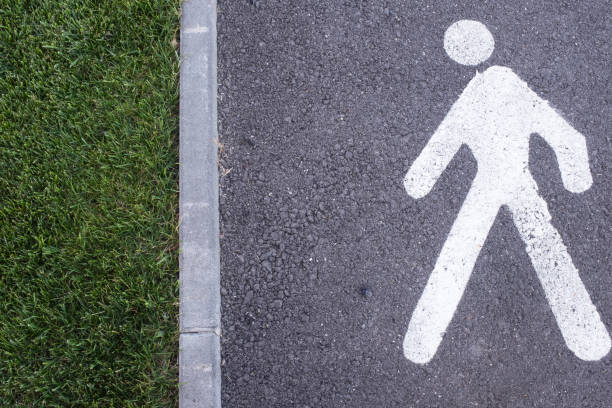 Walk sign white painted on the street, sunshine and shadows on the road, information sign for people, no person