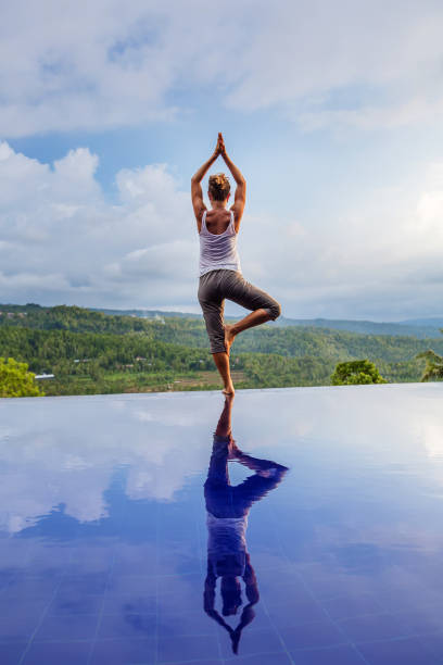 istock Caucasian woman practicing yoga by the pool 1156519575