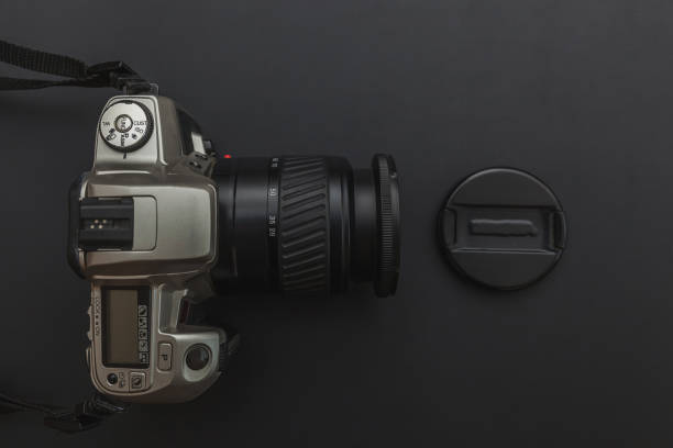 istock Photographer workplace with dslr camera system on dark black table background. Hobby travel photography concept 1156519704