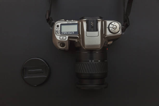 istock Photographer workplace with dslr camera system on dark black table background. Hobby travel photography concept 1156519720