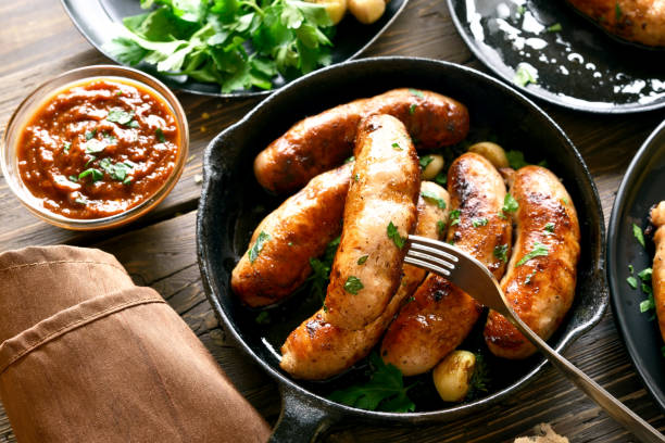 Fried sausages in frying pan Tasty fried sausages in frying pan on wooden table. Close up view sausage stock pictures, royalty-free photos & images