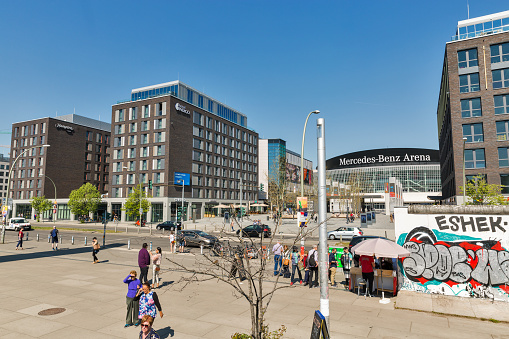 BERLIN, GERMANY - APRIL 18, 2019: People visit Mercedes Platz in front of Mercedes-Benz Arena at sunny day. Berlin is the capital and largest city of Germany by both area and population.