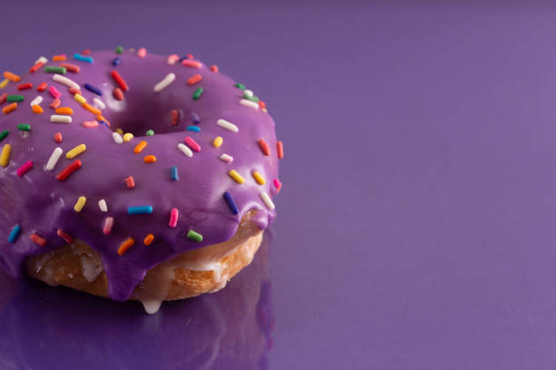 A Purple Glazed Donut with Rainbow Sprinkles on Top