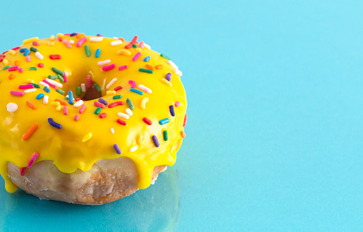 A Yellow Sprinkle Donut on a Blue Background