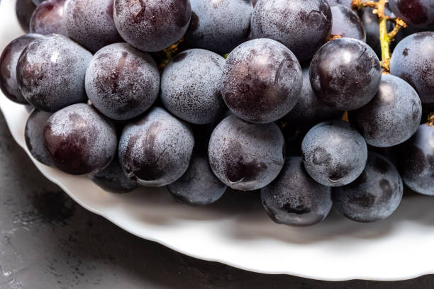 istock bunch of black ripe grapes on a white plate 1156522558