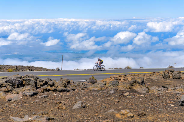 雲の上に乗る - ハレアカラ国立公園の標高10,023フィートのハレアカラハイウェイの雲の上に乗る女性の自転車。マウイ島、 ハワイ、 アメリカ合衆国。 - haleakala national park ストックフォトと画像