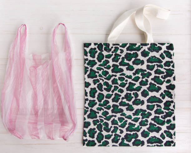 istock Eco Shopping Bag with trendy leopard pattern print against a plastic bag on white wooden background, Flat Lay. Save planet earth 1156523700
