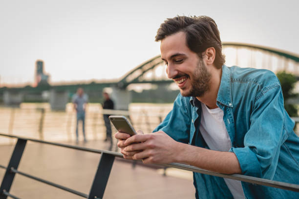 istock a young man uses smartphone while standing outdoor 1156526364