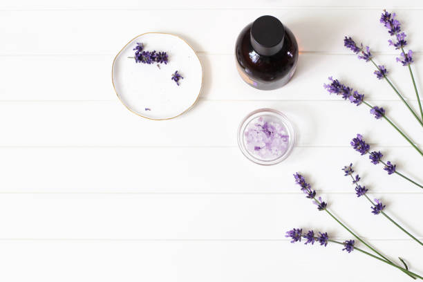 istock Styled summer beauty composition. Essential, massage oil, purple lavender flowers and bath salt on white wooden table background. Organic herbal cosmetics, spa concept. Empty space, flat lay, top view. 1156528708