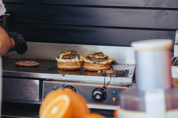istock Cook preparing burger adding the sauce on the cream cheese. Three burgers. 1156529870