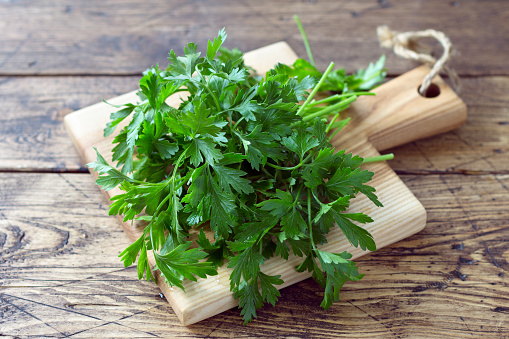 Bunch of fresh organic parsley on a cutting board on a wooden table, selective focus, rustic style