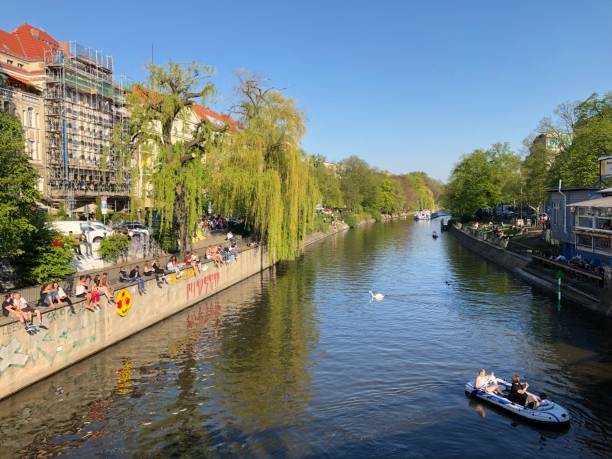 People enjoying sunny weather on the street, sitting at riverside in Berlin, Kreuzberg during spring Berlin, Germany - april 2019: People enjoying sunny weather on the street, sitting at riverside in Berlin, Kreuzberg during spring kanal stock pictures, royalty-free photos & images