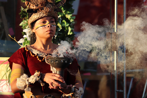 Moscow, Russia - June 2019: Girl as a Mayan Priestess performs an ancient ritual of fire on on Manezh square on Moscow historical festival Times and epochs. Performance by the Mexican group Xipetotek, reenactors of historyof Maya