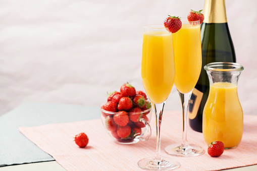Two glasses of mimosa cocktail (champagne with orange juice) and fresh strawberries