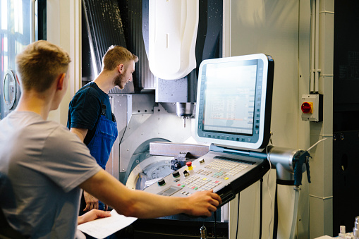 Industry 4.0: two young engineers control work on a CNC machine