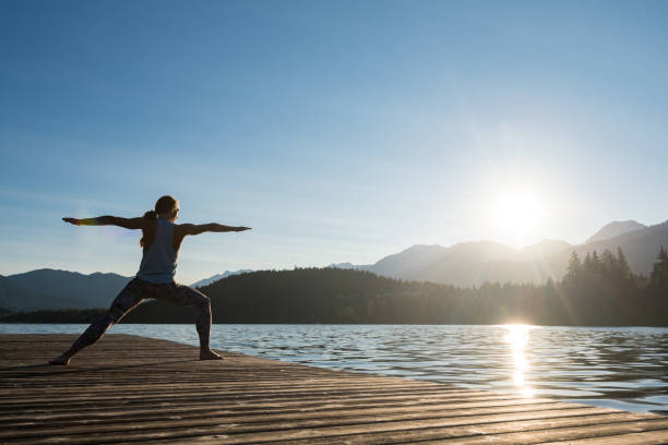 istock Female doing warrior 2 pose on dock in Whistler 1156534945