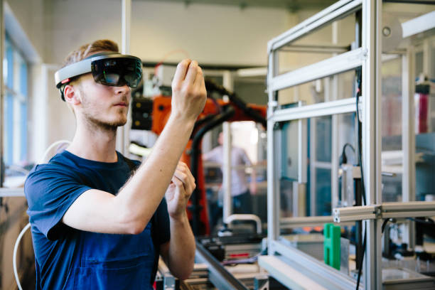 industria 4.0: un joven ingeniero trabaja con una pantalla montada en la cabeza - robot fotos fotografías e imágenes de stock