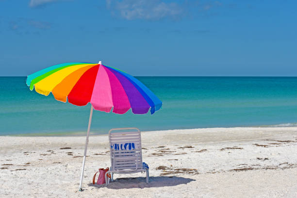 Beach Umbrella Colorful Umbrella and Chair on the Sandy Beaches of Anna Maria Island beach umbrella stock pictures, royalty-free photos & images
