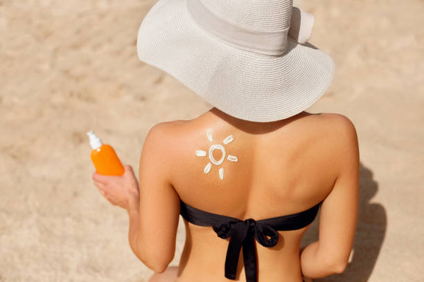 Woman Applying Sun Cream on Tanned Shoulder In Form Of The Sun. Sun Protection.Sun Cream. Skin and Body Care. Girl Using Sunscreen to Skin. Female Holding Suntan Lotion and Moisturizing Sunblock. mujer aplicando crema solar sobre el hombro curtido en forma de la protección solar.sun cream. cuidado de la piel y el cuerpo. chica usando protector solar para la piel. loción de bronceado de sujeción femenina y bloqueador solar hidratante.