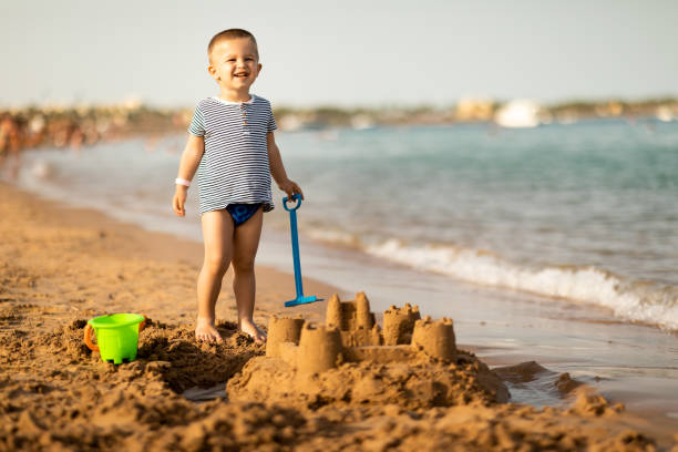 istock Cute little baby boy playing with sand on a beach 1156550587