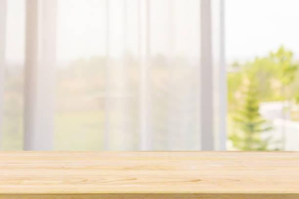 istock Empty wood table top with window curtain abstract blur background for product display 1156572934