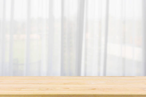 istock Empty wood table top with window curtain abstract blur background for product display 1156572942